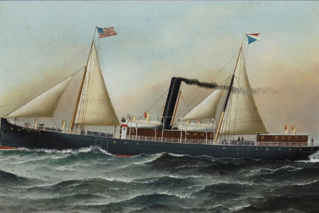 Historic steam-and-sail hybrid vessel navigating rough ocean waters with billowing sails, black smokestack exhaust, and maritime flags flying above the deck.